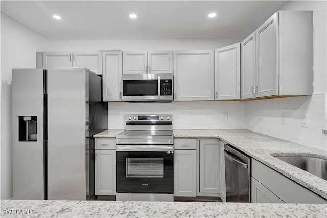 kitchen featuring backsplash, gray cabinets, light stone countertops, and stainless steel appliances