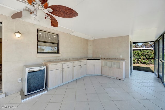 kitchen featuring ceiling fan, light brown cabinetry, and tile walls