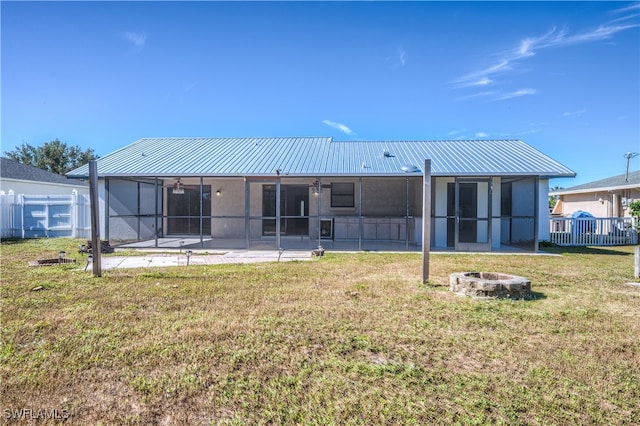 back of property with a lawn, a patio, and an outdoor fire pit