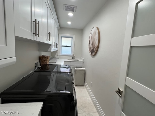 laundry area featuring washer and dryer, sink, light tile patterned floors, and cabinets