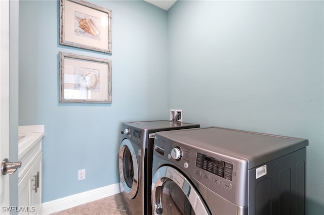 clothes washing area with washer and clothes dryer, light tile patterned flooring, and cabinets