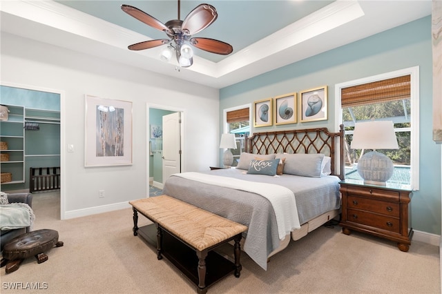 bedroom with light carpet, a raised ceiling, ceiling fan, connected bathroom, and a closet