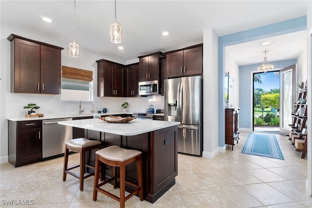 kitchen featuring a center island, dark brown cabinetry, stainless steel appliances, and hanging light fixtures