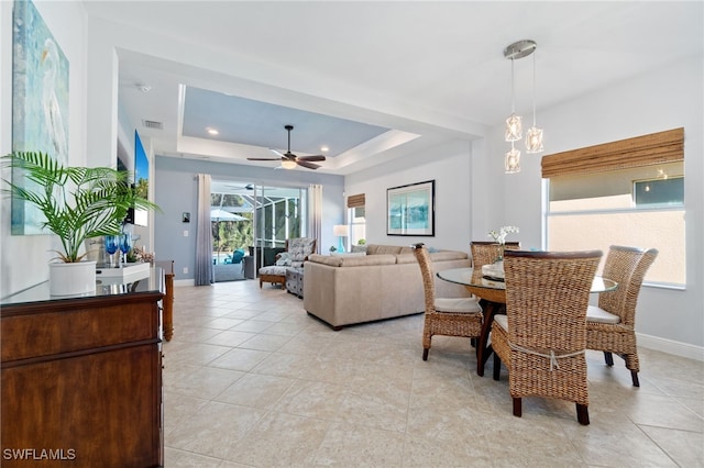 tiled dining room featuring a tray ceiling and ceiling fan