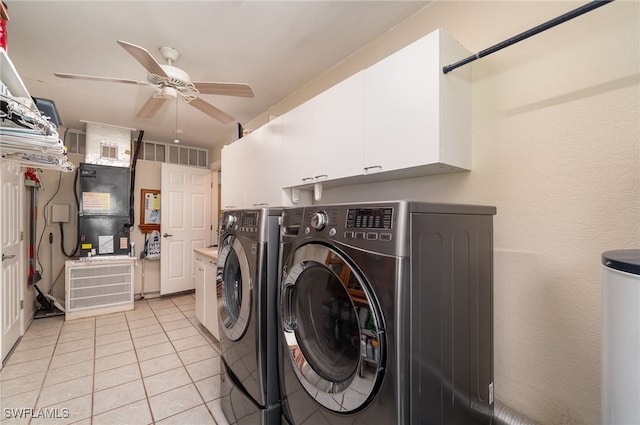 laundry area with cabinets, heating unit, ceiling fan, light tile patterned floors, and washing machine and dryer