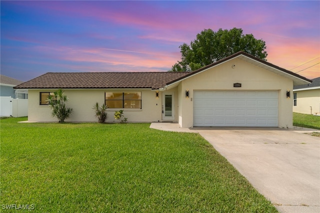 single story home featuring a lawn and a garage