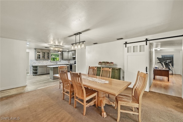 dining room featuring a barn door and light hardwood / wood-style flooring