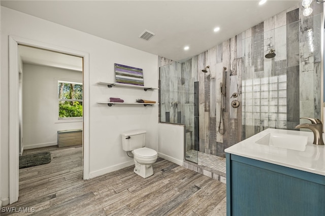 bathroom featuring tiled shower, hardwood / wood-style floors, vanity, and toilet