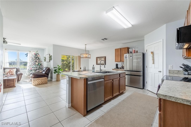 kitchen featuring appliances with stainless steel finishes, sink, decorative light fixtures, an island with sink, and light tile patterned flooring