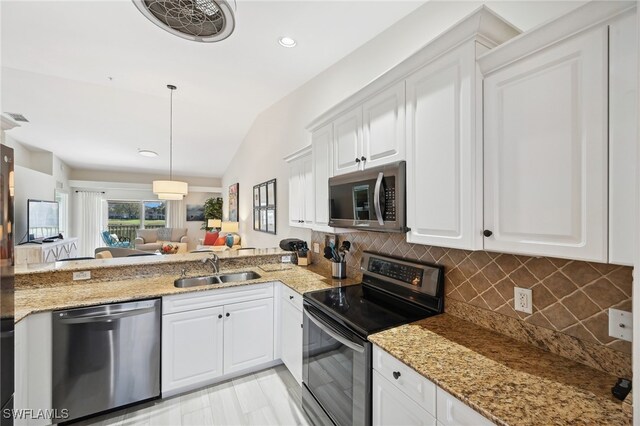 kitchen with pendant lighting, lofted ceiling, sink, appliances with stainless steel finishes, and white cabinetry