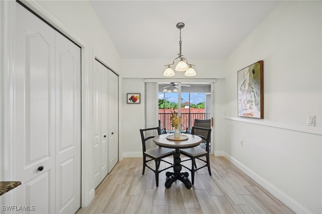 dining space with light hardwood / wood-style floors and an inviting chandelier