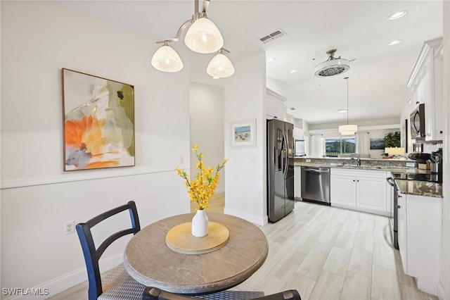 dining space with light wood-type flooring and sink