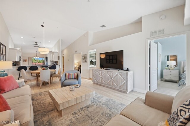 living room featuring high vaulted ceiling and light hardwood / wood-style flooring