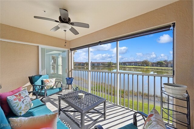 sunroom with ceiling fan and a water view