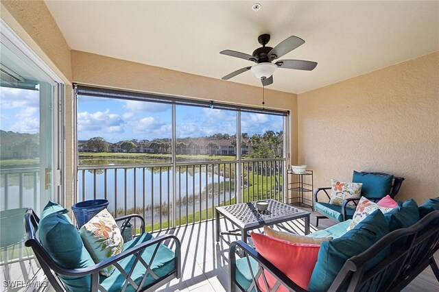 sunroom / solarium featuring ceiling fan and a water view