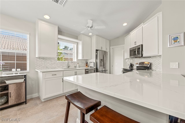 kitchen with white cabinetry, sink, a kitchen breakfast bar, kitchen peninsula, and appliances with stainless steel finishes