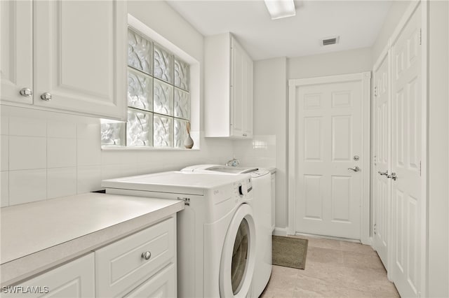 laundry area featuring washer and dryer, light tile patterned flooring, and cabinets