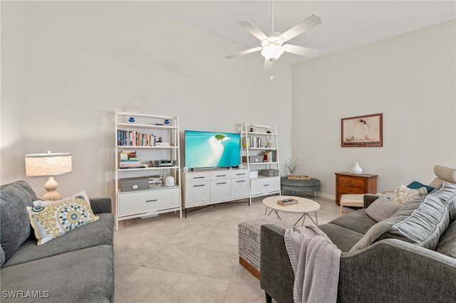 tiled living room featuring ceiling fan and a towering ceiling