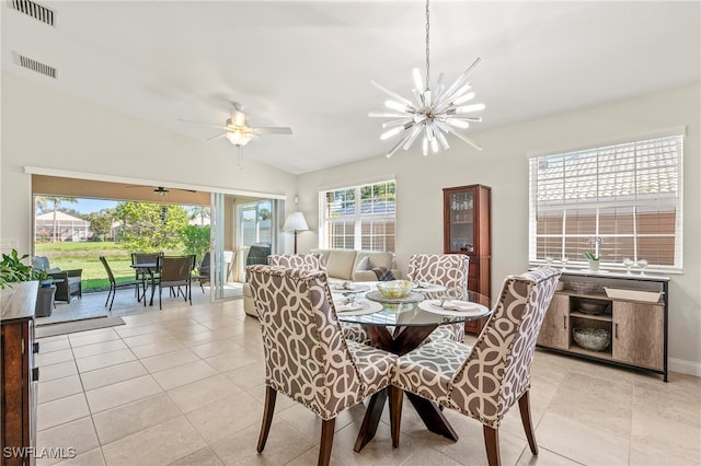 dining area with light tile patterned floors, ceiling fan with notable chandelier, a healthy amount of sunlight, and lofted ceiling