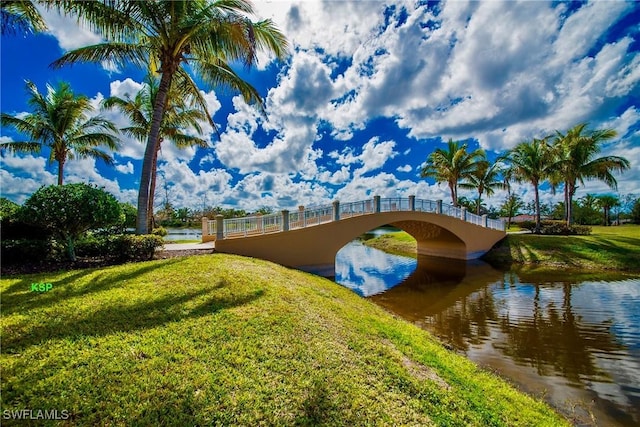 surrounding community with a water view and a yard