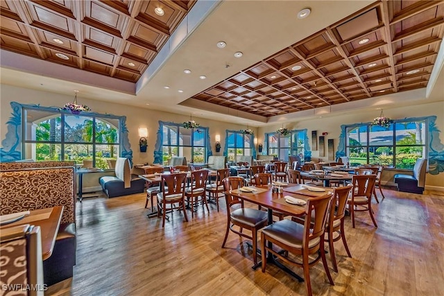 dining room with coffered ceiling, a notable chandelier, and light hardwood / wood-style flooring