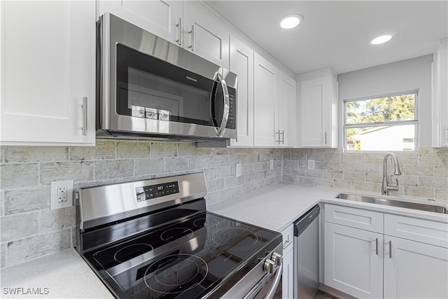 kitchen featuring decorative backsplash, white cabinetry, sink, and appliances with stainless steel finishes