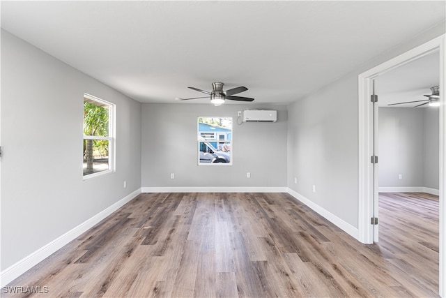 unfurnished room featuring an AC wall unit, ceiling fan, and light wood-type flooring