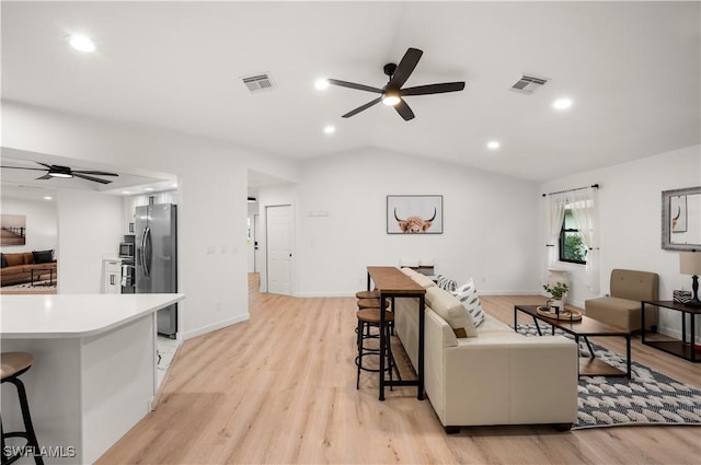 living room featuring light wood-type flooring, vaulted ceiling, and ceiling fan