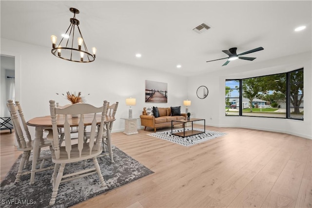 dining room with light wood-type flooring and ceiling fan with notable chandelier