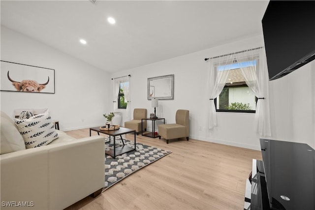 living room with a healthy amount of sunlight, light hardwood / wood-style flooring, and lofted ceiling