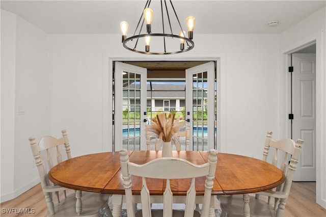 dining room featuring light wood-type flooring, french doors, and an inviting chandelier