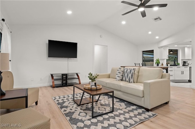 living room featuring ceiling fan, light hardwood / wood-style flooring, and vaulted ceiling