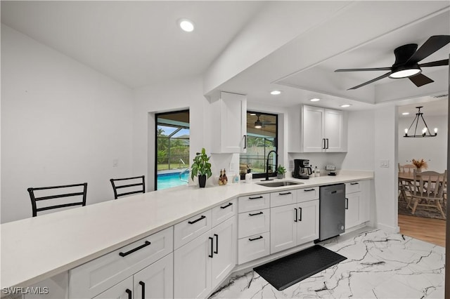 kitchen featuring sink, dishwasher, hanging light fixtures, and white cabinets