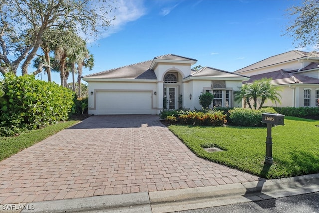 mediterranean / spanish home featuring a front lawn and a garage