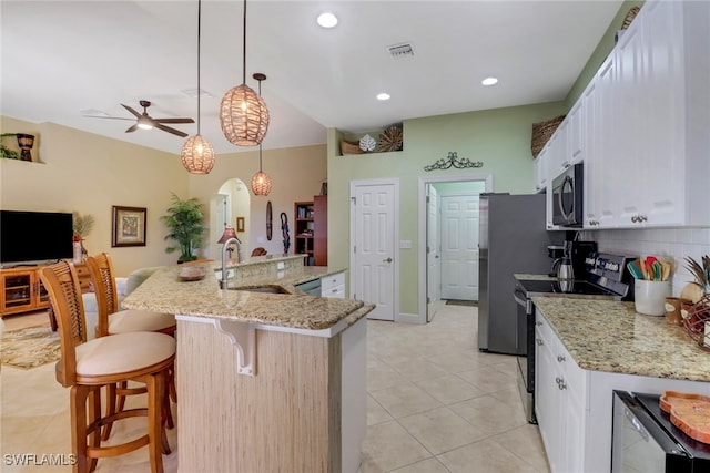 kitchen with appliances with stainless steel finishes, sink, a center island with sink, white cabinetry, and hanging light fixtures