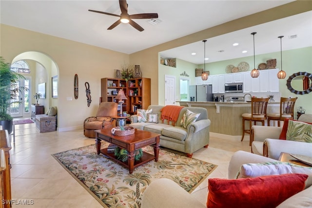 tiled living room with ceiling fan and sink