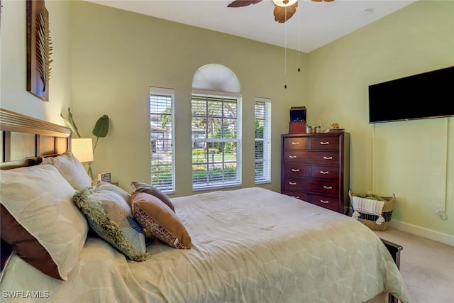 bedroom with ceiling fan, light colored carpet, and a high ceiling