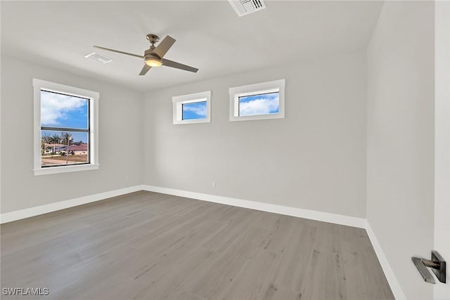 empty room with baseboards, visible vents, ceiling fan, and wood finished floors