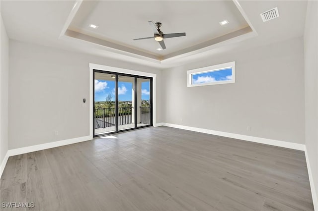 empty room with hardwood / wood-style floors and a raised ceiling