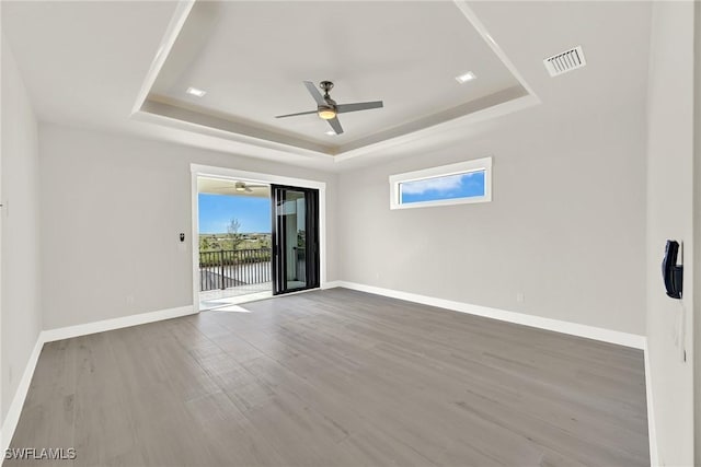 spare room featuring hardwood / wood-style floors, a raised ceiling, and ceiling fan