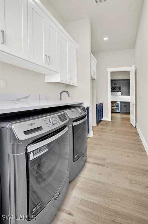 laundry room featuring light hardwood / wood-style floors, cabinets, and separate washer and dryer