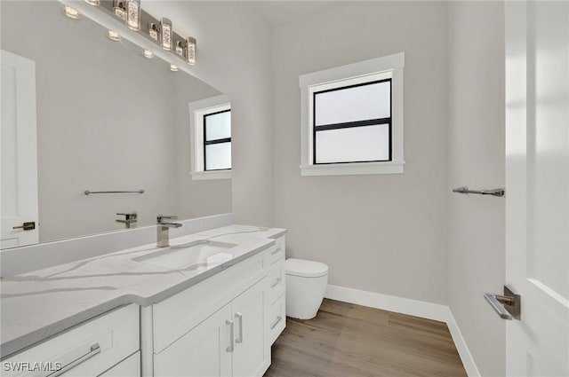 bathroom with toilet, baseboards, wood finished floors, and vanity