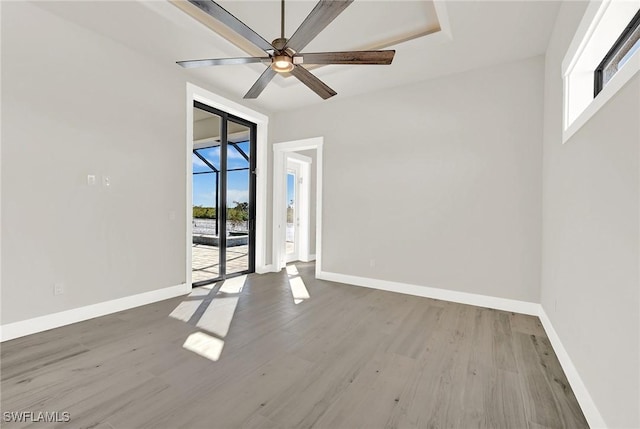 unfurnished room with wood finished floors, a ceiling fan, and baseboards