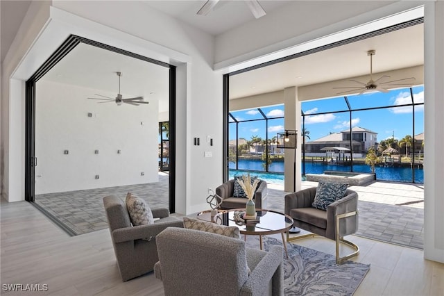 interior space with ceiling fan, plenty of natural light, a sunroom, and a water view