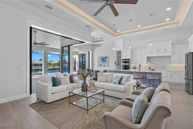 living room with a tray ceiling and light hardwood / wood-style flooring