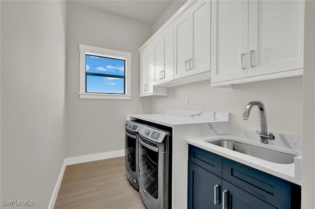 washroom with washing machine and dryer, cabinets, sink, and light hardwood / wood-style floors