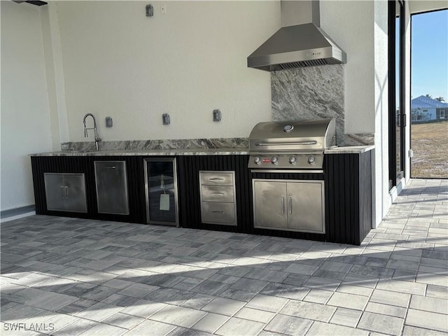 kitchen featuring sink, stainless steel refrigerator, and wall chimney range hood