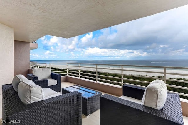 balcony featuring an outdoor living space, a water view, and a view of the beach