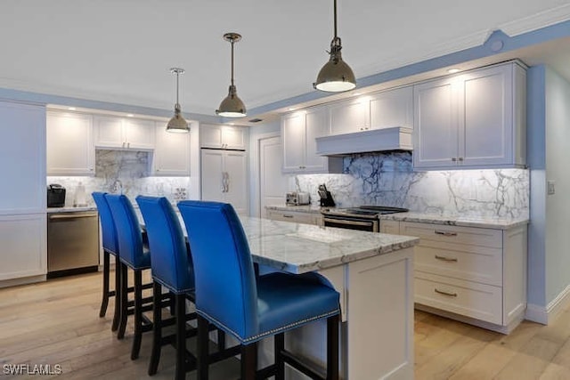 kitchen with a breakfast bar, a center island, hanging light fixtures, appliances with stainless steel finishes, and light stone counters