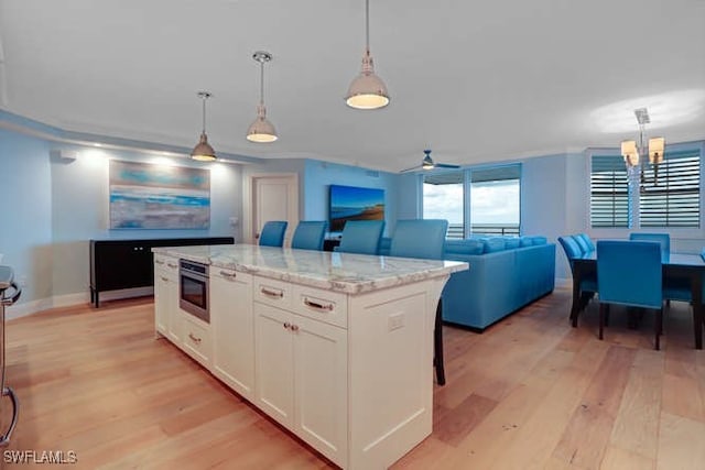 kitchen with a breakfast bar area, white cabinetry, a kitchen island, and pendant lighting